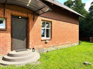 a brick house with a black door and a window at Tūja apartment with private entrance and garden in Tūja