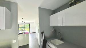 Una cocina con gabinetes blancos y un fregadero. en Le confort contemporain dans un écrin de verdure, en Vernon 43 fotos más