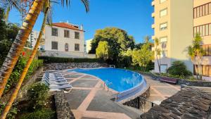 una piscina junto a un edificio y una palmera en Apto Barreiro by Susy's Holidays, en Funchal