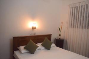 een slaapkamer met een bed met groene en witte kussens bij Villa Green Garden in Hikkaduwa +75 foto's
