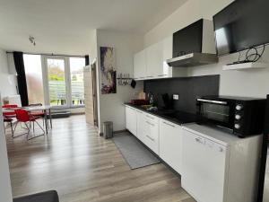 a kitchen with white cabinets and a large window at Chez ida in Heer
