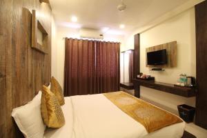 a hotel room with a bed and a television at Marigold Regency in Shirdi