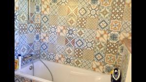 a bathroom with a tub and a tiled wall at Magnifique longère au cœur de Trégastel in Trégastel +29 photos