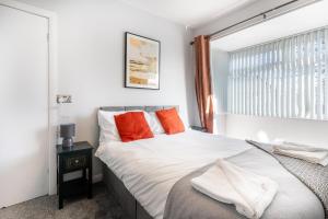 a bedroom with a bed with orange pillows and a window at Royal Retreat in Redcar