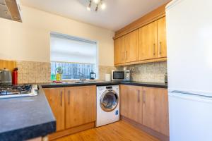 a kitchen with wooden cabinets and a washer and dryer at Royal Retreat in Redcar