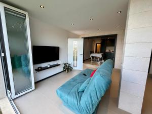 a living room with a blue couch and a flat screen tv at Apartman Mrva in Baošići