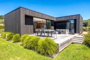 a house with a wooden deck with a table and chairs at Wavesong Mahe in Onetangi