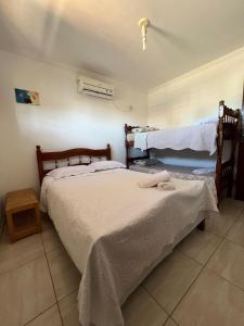 une chambre avec deux lits avec des draps blancs dans l'établissement Casa em Peroba/Maragogi, à Maragogi