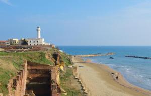 vistas a una playa con un faro en el fondo en Beautiful Home In Nettuno With Wifi, en Nettuno