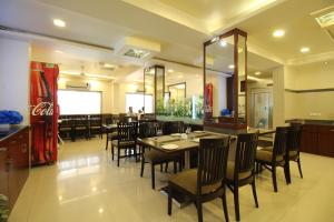 um restaurante com mesas e cadeiras e uma máquina de coca-cola em Marigold Regency em Shirdi