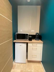 a small kitchen with a microwave and a refrigerator at La p'tite hirondelle in Les Magnils-Reigniers +6 photos