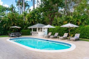 a swimming pool with patio furniture and umbrellas at Royal Palms, St James in Saint James