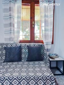 a bed with blue pillows in front of a window at Cypress Seaside Apartment #PROPERTLY in Nea Kallikrateia