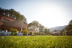 a lawn with chairs and umbrellas in front of a building at Hotel Bersè in Borgo Val di Taro