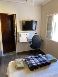 a bedroom with a bed and a desk and a chair at Pousada São Luiz in Bragança Paulista