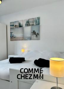 a bedroom with a white bed with four pictures on the wall at Studio Le Petit Placieux, Garage Gratuit sur place in Nancy