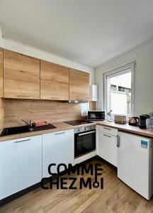 a kitchen with white appliances and wooden cabinets at Studio Le Petit Placieux, Garage Gratuit sur place in Nancy