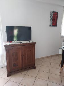 a flat screen tv sitting on top of a wooden cabinet at Pin parasol in Marmande