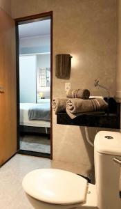 a bathroom with a mirror and a toilet and a bed at Casa Flor de Jacarandá in Alto Paraíso de Goiás