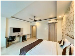 马图拉HOTEL K R - PREMIUM Near Krishna JanamBhoomi - Mathura Railway Juction - Bus stand - Parking and Wifi Facilities - Air Conditioning Luxury Room - A Top Rated Four Star Hotel的一间卧室，配有一张床、一张书桌和一台电视