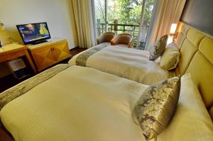 Habitación de hotel con 2 camas y TV en Jun Yue Hanging Garden Resort, en Renai