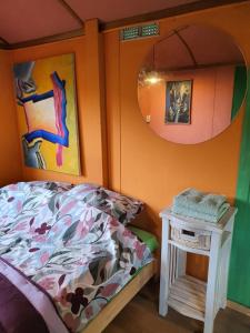 a bedroom with a bed and a mirror and a table at Pipowagen Doe Maar Groen in Bant +1 photo