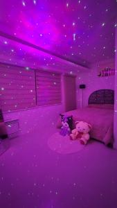 zwei Teddybären sitzen auf einem Bett mit lila Lichtern in der Unterkunft Anna's cozy house in Angeles