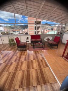 a living room with wooden floors and chairs and windows at Magic Cusco in Cusco