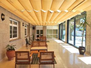 a covered porch with chairs and tables and windows at Hotel Miramar Playa America Nigran in Nigrán