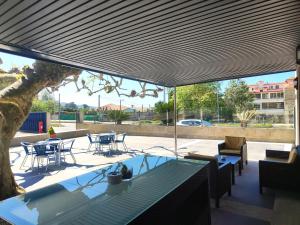 a patio with tables and chairs and a tree at Hotel Miramar Playa America Nigran in Nigrán