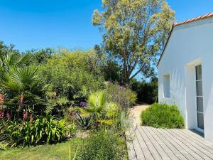 un giardino con una passerella di legno accanto a un edificio bianco di Au cœur de Trégastel, noyée dans la végétation a Trégastel