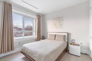 a white bedroom with a bed and a window at Centrally Located Luxury Home with Views and Cinema in Vancouver