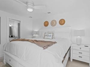 een witte slaapkamer met een wit bed en een spiegel bij Sand And Sea Bungalow in Naples