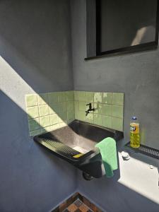 a bathroom with a sink and a green tile wall at Lofts 4 Elementos - Terra - Martim de Sá - Caraguatatuba in Caraguatatuba +24 photos