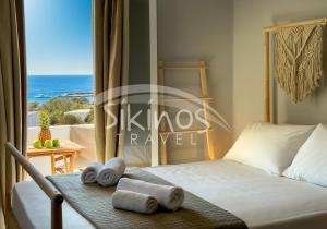 a bedroom with a bed and a view of the ocean at Galini Rooms Sikinos Travel in Síkinos