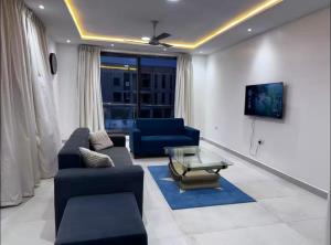 a living room with blue couches and a tv at Beautiful 2-bed apartment East Legon in Ajiringano