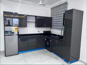 a kitchen with black cabinets and a refrigerator at Beautiful 2-bed apartment East Legon in Ajiringano +4 photos