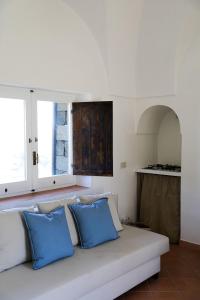 a white couch with blue pillows in a living room at Dammusi Futura in Pantelleria +51 photos