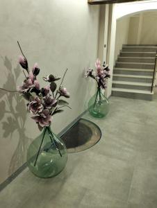 zwei Vasen mit Blumen darin auf einem Boden in der Unterkunft Smartroom Lula di Correggio in Correggio