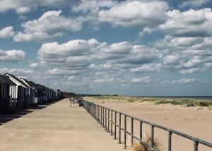 a boardwalk on a beach with houses on it at Quiet Equestrian Retreat - Sleeps 4 in Trusthorpe