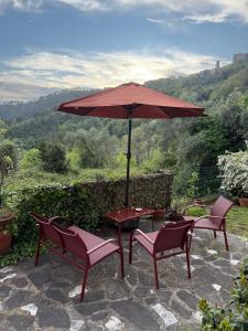 a patio with a table and chairs and an umbrella at La Casetta Valdonica La Spezia in Calice al Cornoviglio
