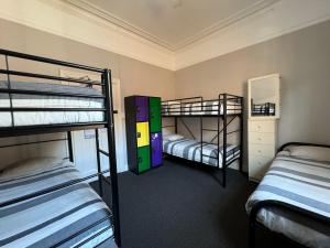 a room with three bunk beds and a mirror at Manly Bunkhouse in Sydney