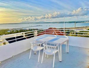 einen weißen Tisch und Stühle auf einem Balkon mit Blick auf das Wasser in der Unterkunft CASA n'A COSTA in Trafaria