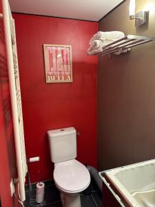 a bathroom with a toilet and a red wall at La maison de Vouziers in Vouziers