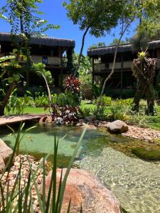 a pond in a garden with a building in the background at Boa Village- Bungalow com Piscina Natural- Praia de Algodões in Marau