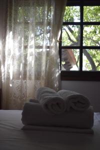 a stack of towels on a bed in front of a window at Villa Viviana in Milina +15 photos