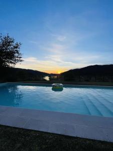 a large swimming pool with a sunset in the background at Caniçada Home in Vieira do Minho