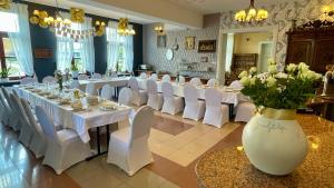 sala bankietowa z białymi stołami i krzesłami oraz wazonem z kwiatami w obiekcie HOTEL - Pałac Słonowice w mieście Brzeżno