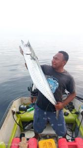 a man holding a fish in a boat in the water at Ombar Guest House in Minyaifuin +192 photos