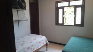 a room with a bed and a window and a table at Cantinho da Dê in Anchieta